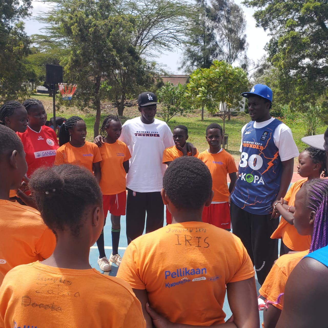 Girls and coaches gathered on a basketball court in Kenya